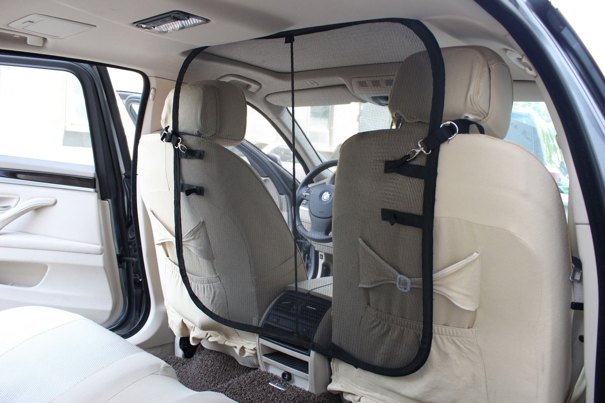 Backseat safety barrier for dogs installed between front seats of car to keep pet secure
