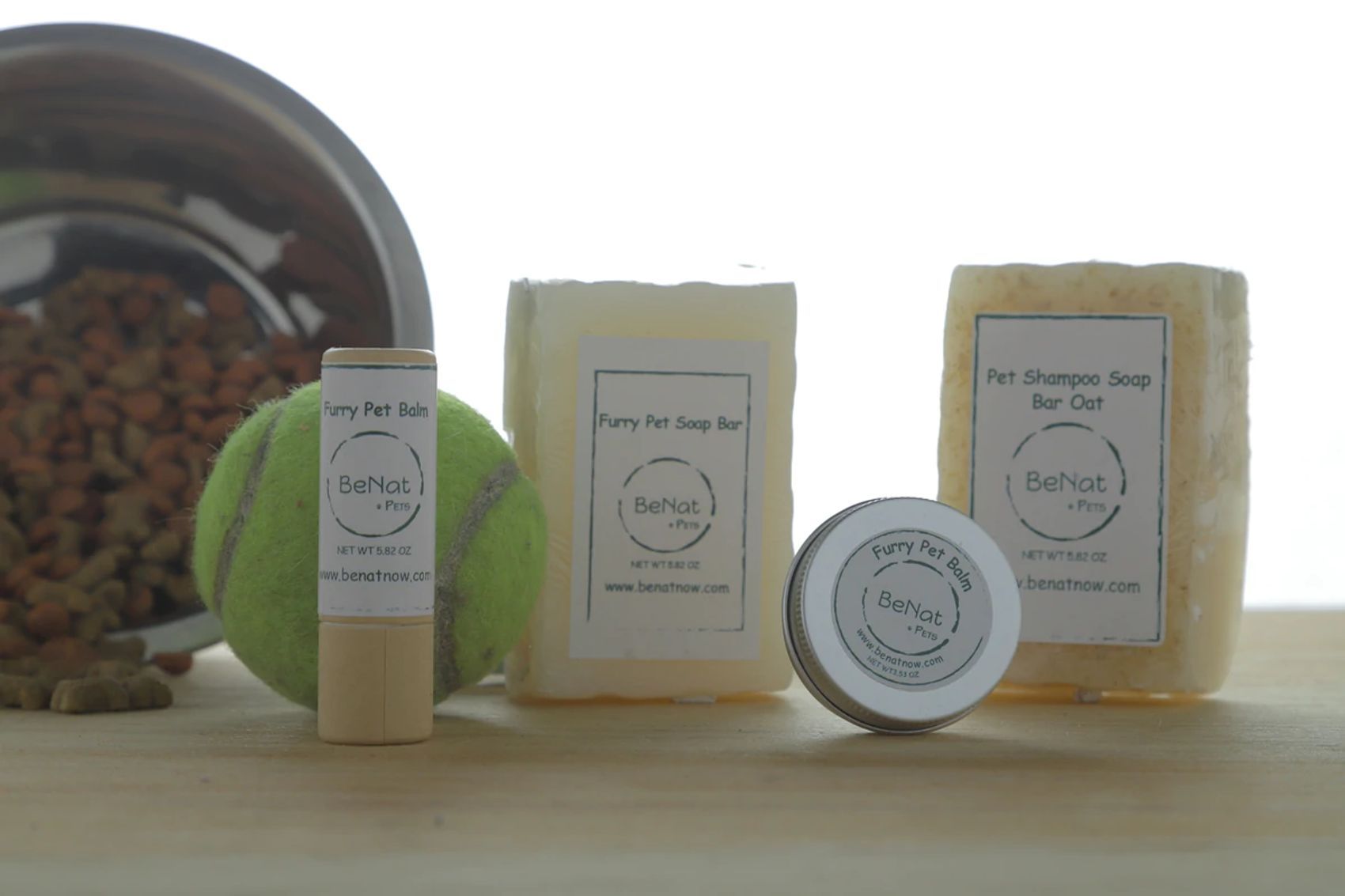 Pet grooming bundle from PawCounter.com with pet shampoo soap bars, balm, and tennis ball on wooden surface