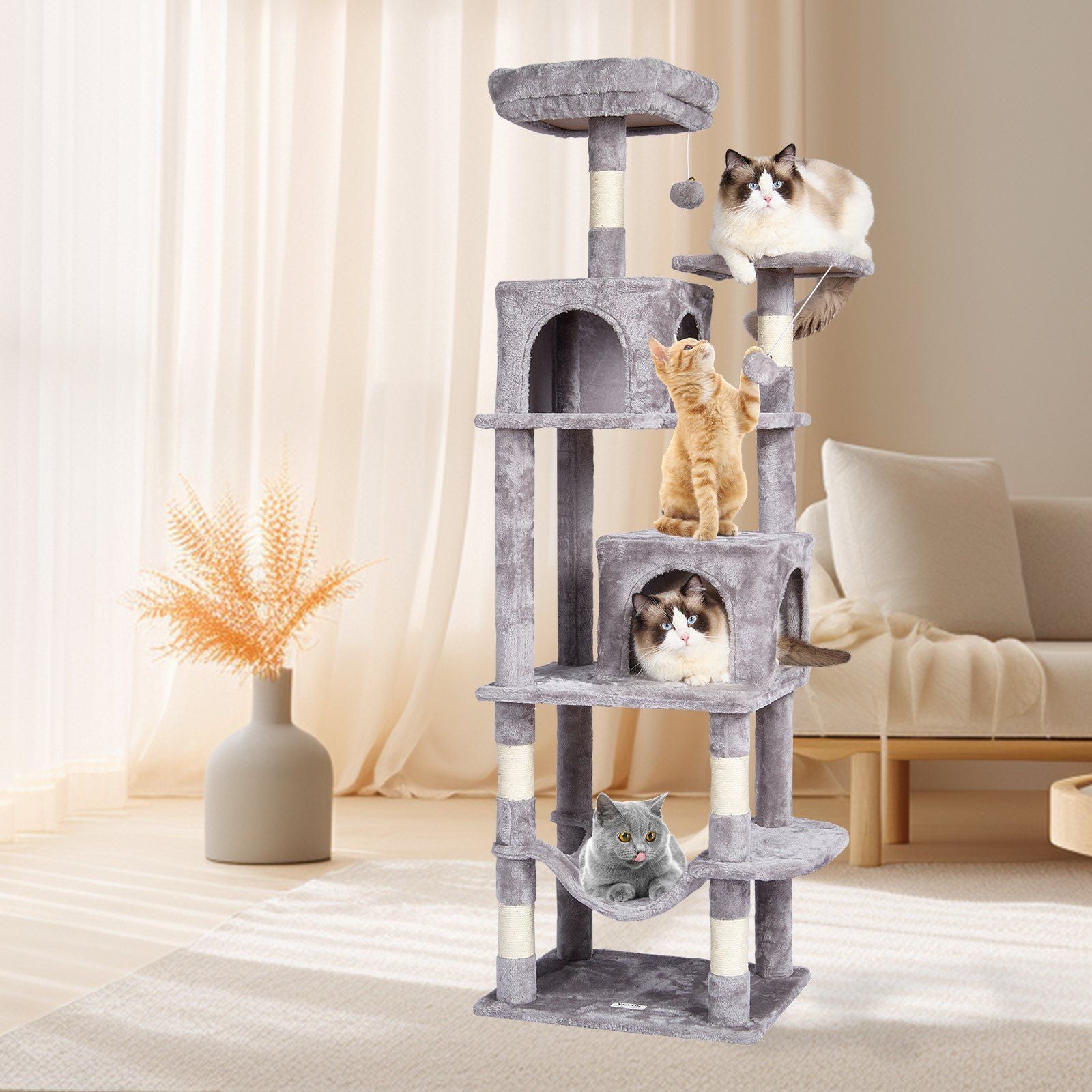 Three cats playing on a tall cat tree with condos and scratching posts in a bright living room