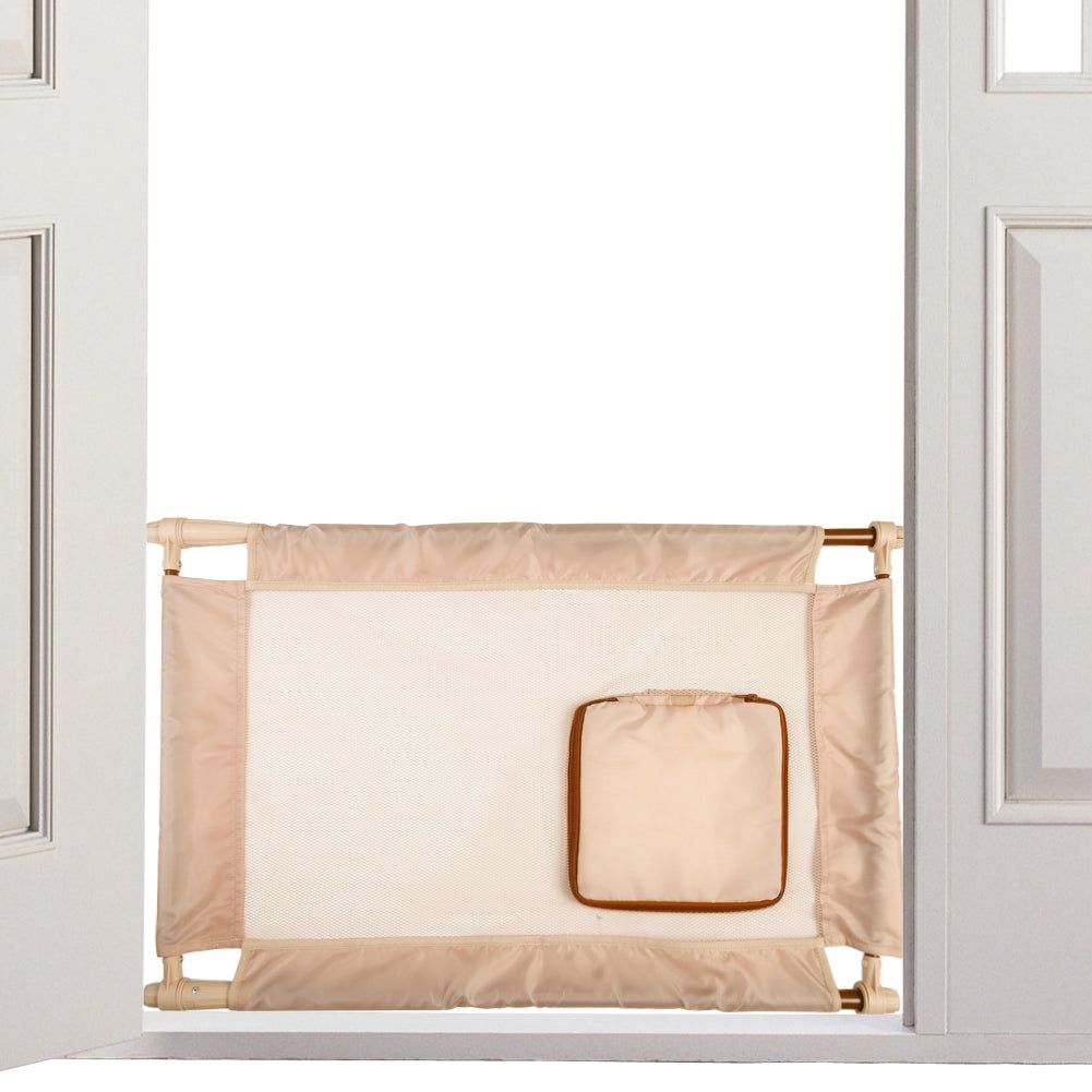 Beige collapsible pet gate for travel installed in a white door frame with carrying pouch attached