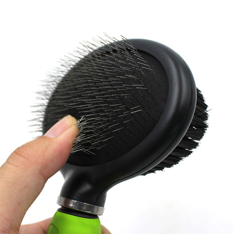 Dual-sided pet grooming brush with metal pins and soft bristles held by hand for pet care
