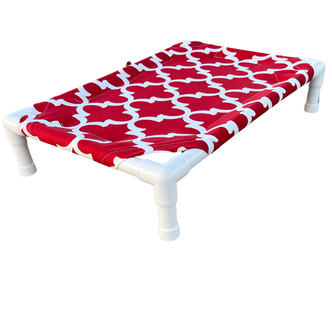 The Family Pet elevated pet bed with white frame and red fabric featuring white bone pattern
