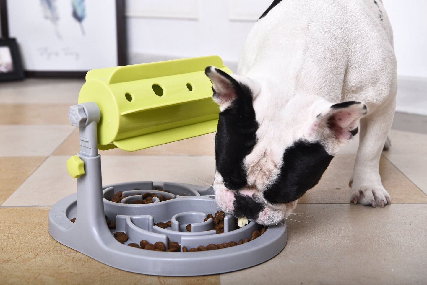 French Bulldog eating from a yellow and gray interactive dog puzzle feeder on tiled floor