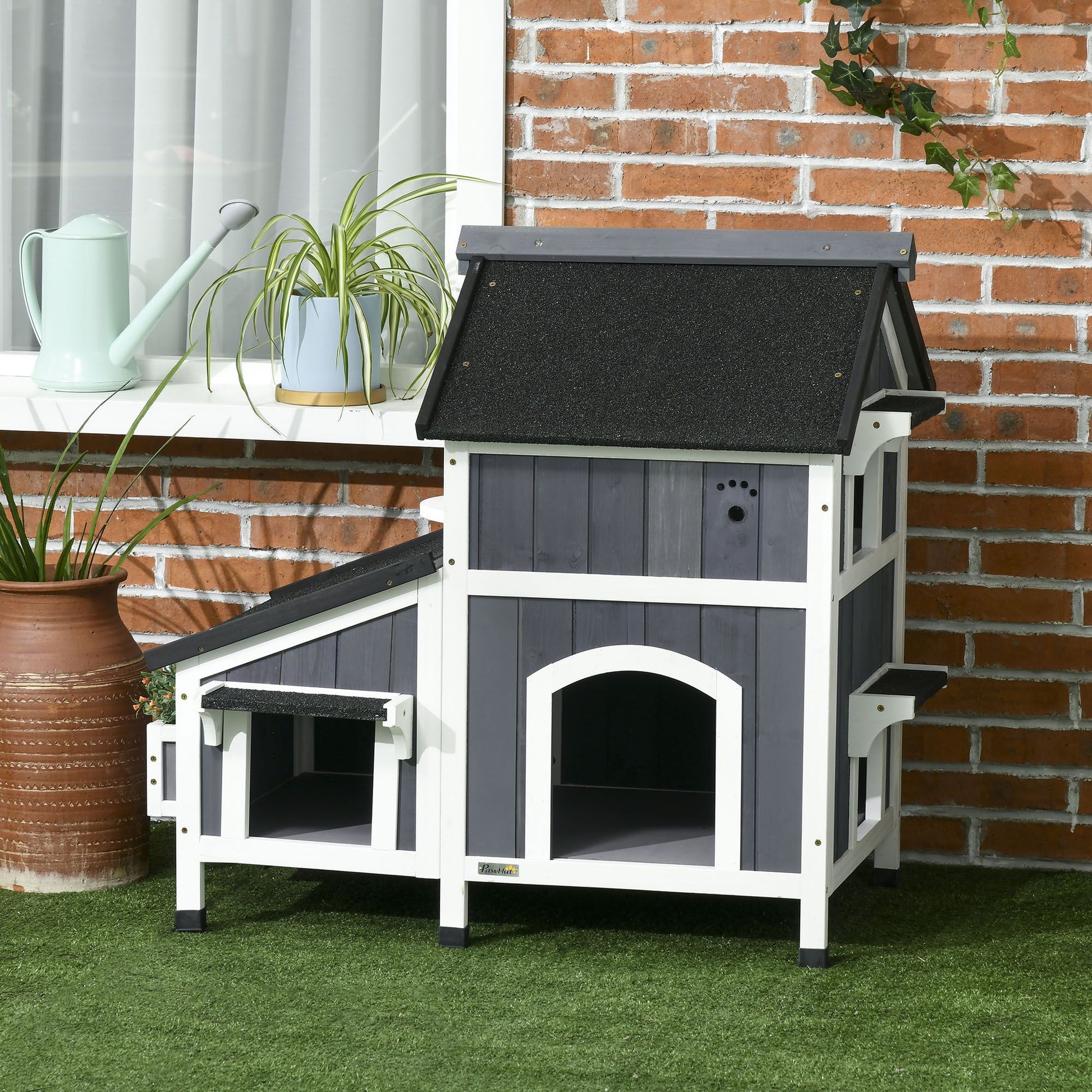Outdoor cat house with flower pot design in gray and white with black roof on green grass