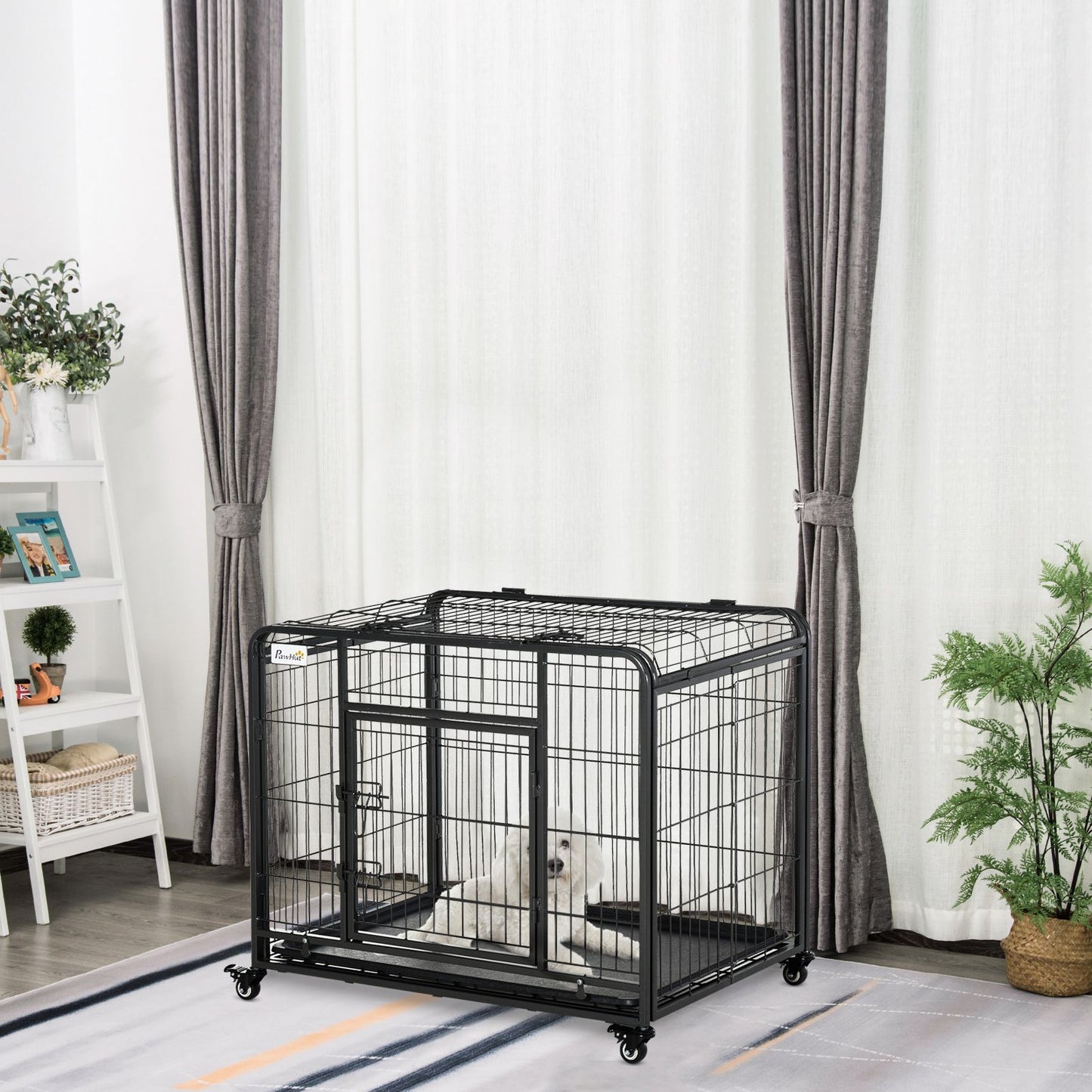 Black heavy duty dog crate with wheels placed indoors on a rug with a small dog inside
