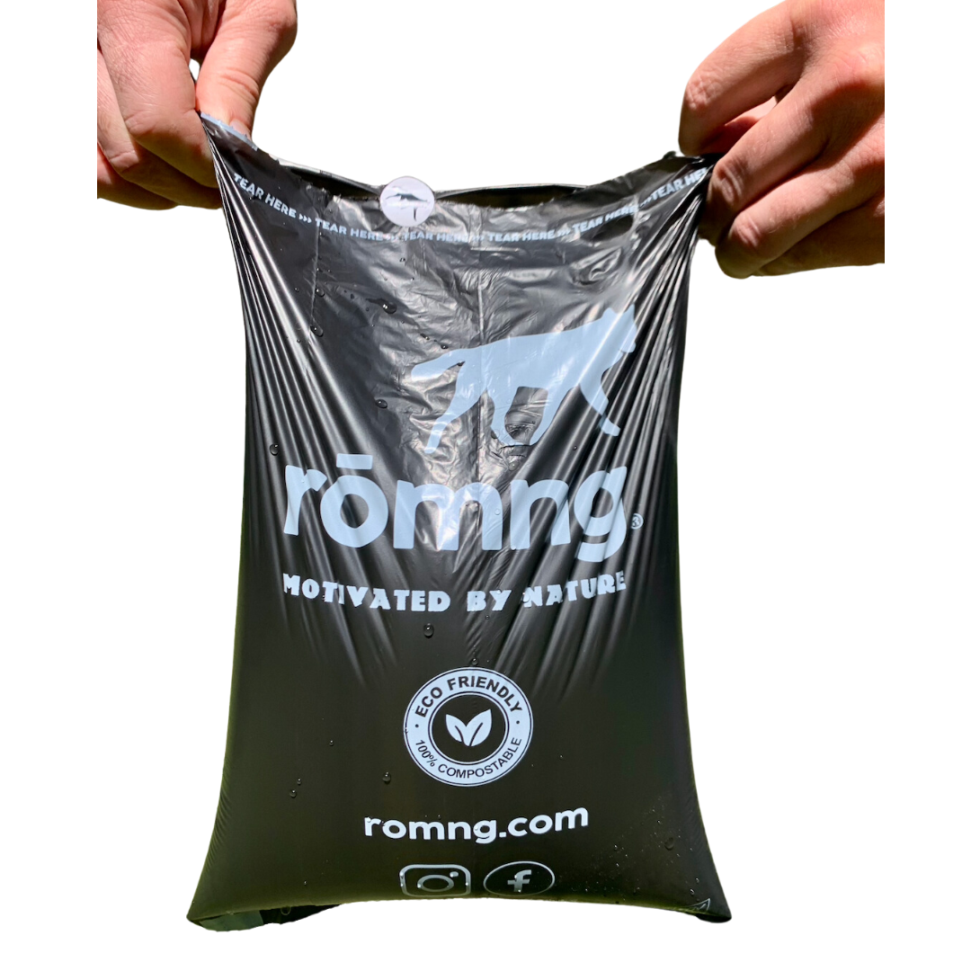 Hands holding rōmng compostable dog poop bags, showcasing their eco-friendly design and durability