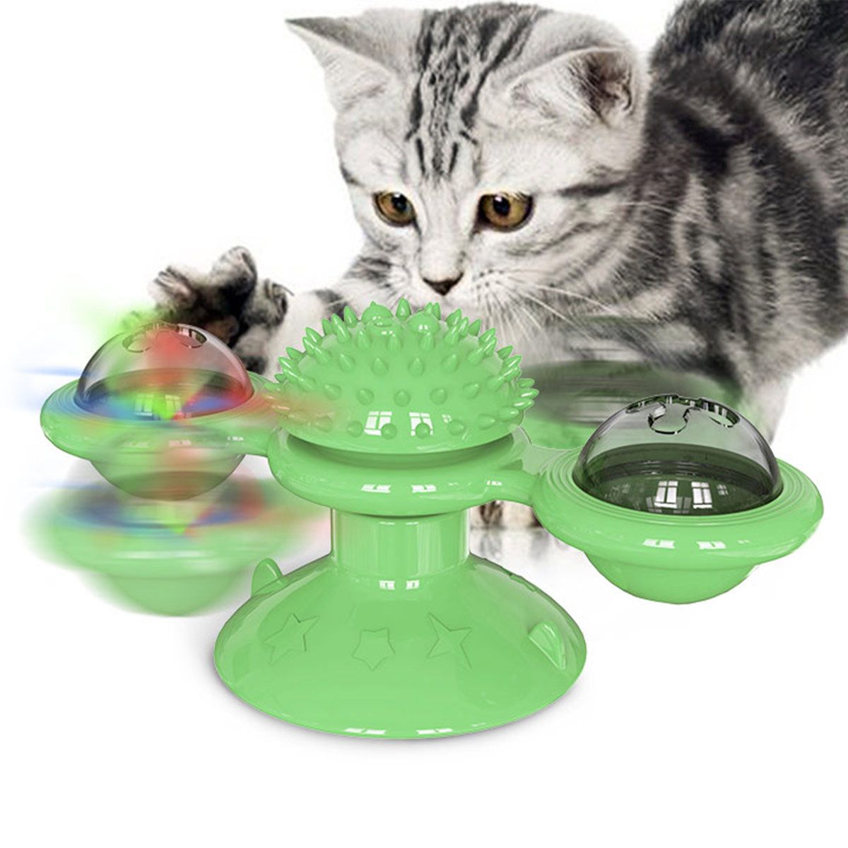Green spinning cat toy with textured center and dome features entertaining a playful gray tabby cat