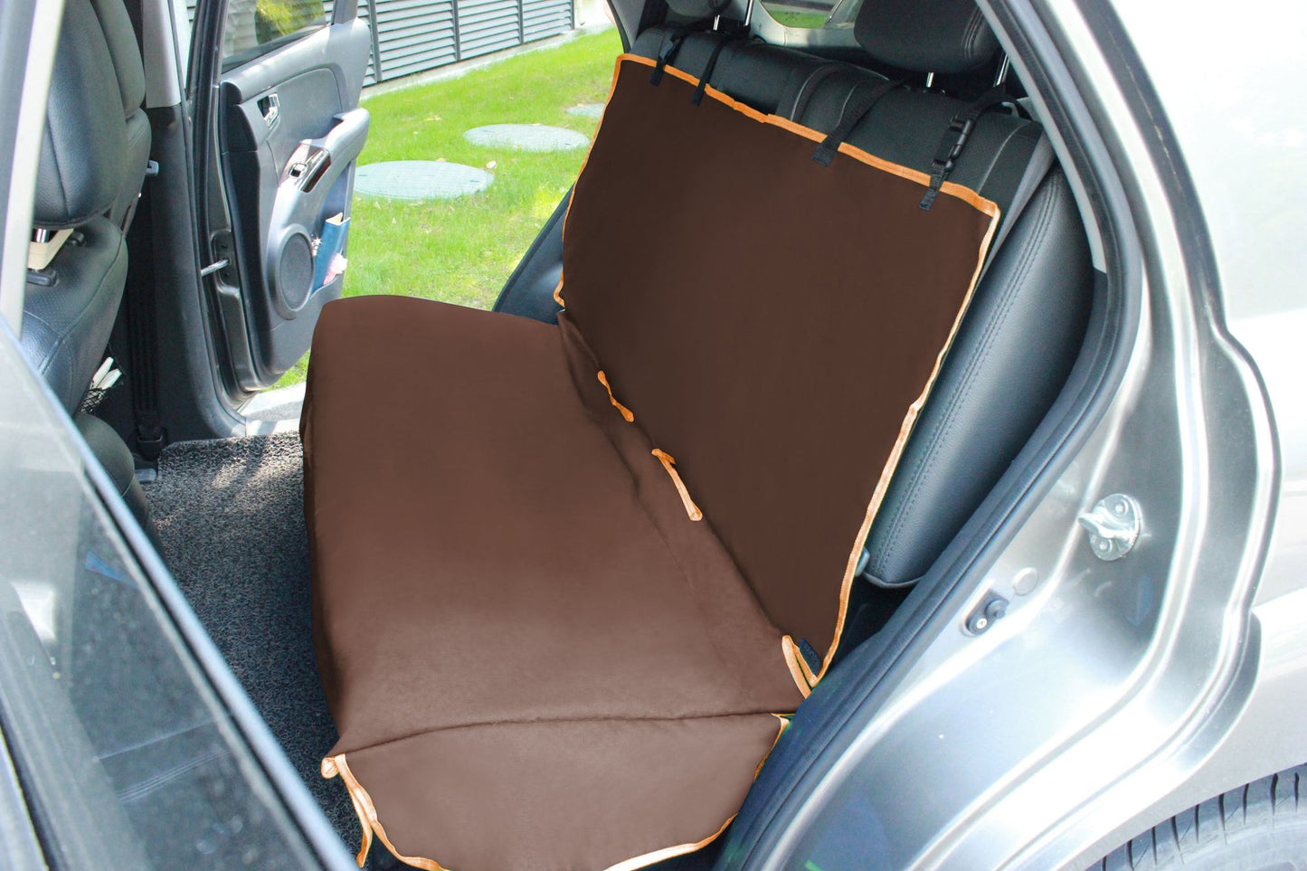 Brown pet car seat protector covering back seat of a silver car with orange trim