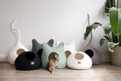 Cozy collection of cat cave beds in various colors with a playful kitten inside a green cat cave bed