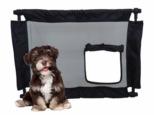 Collapsible pet gate for travel with mesh panel and small door next to a sitting brown and white puppy