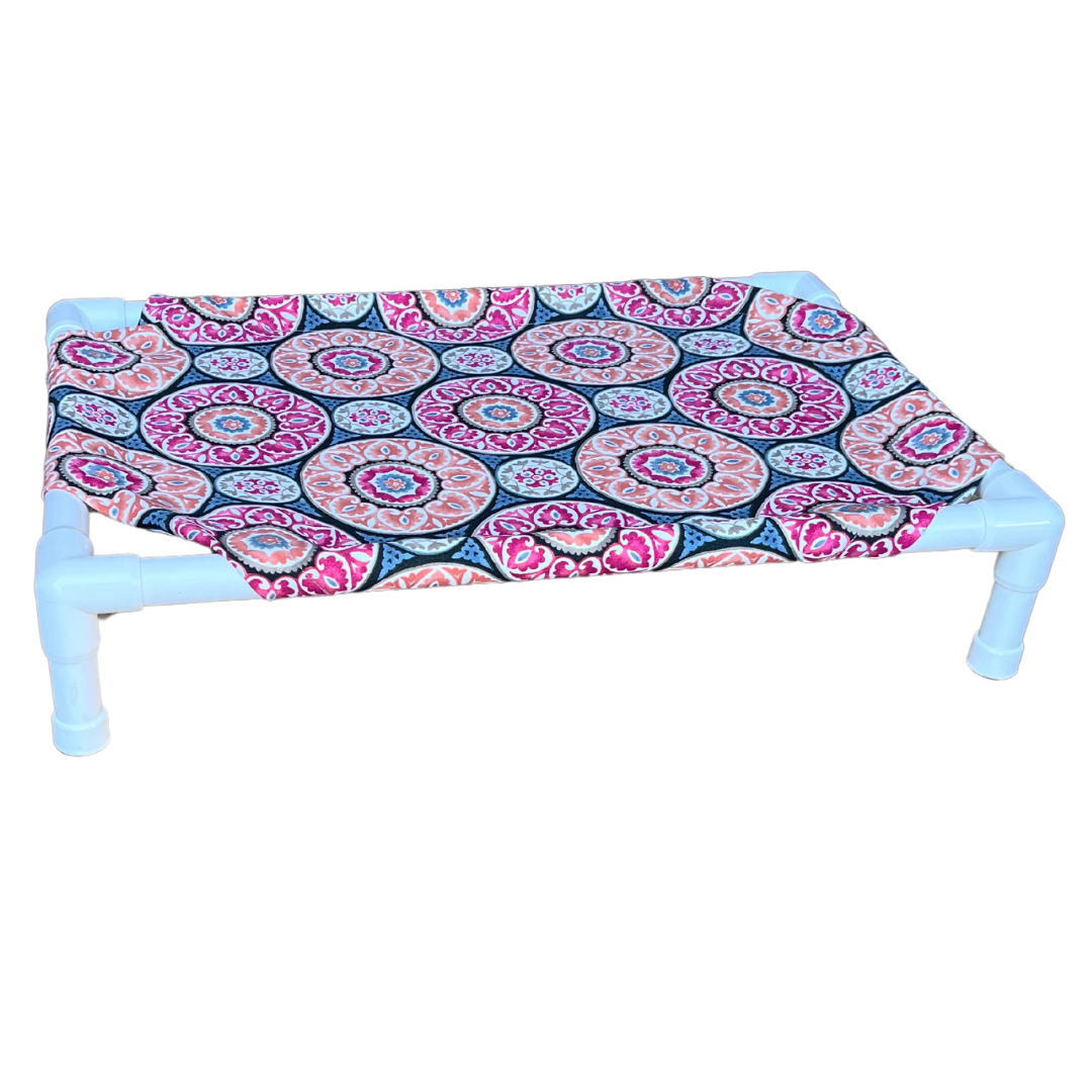 The Family Pet elevated pet bed with white frame and colorful circular patterned fabric