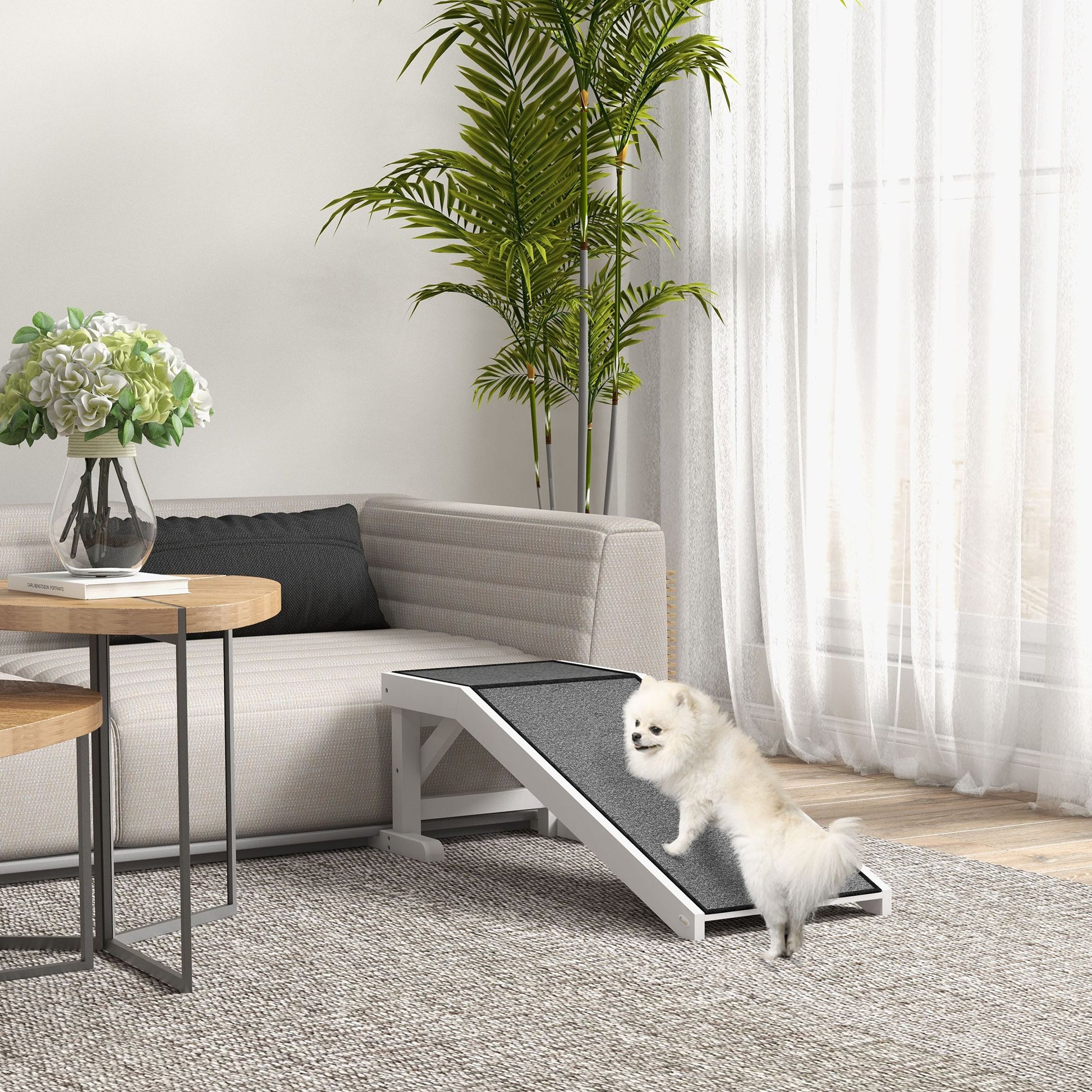 White dog using gray dog ramp for bed next to modern sofa in a bright living room