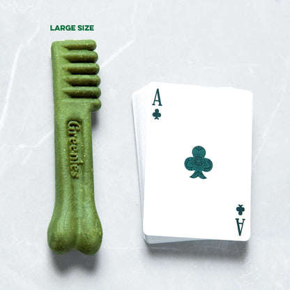 Greenies dental treats for large dogs next to a playing card for size reference