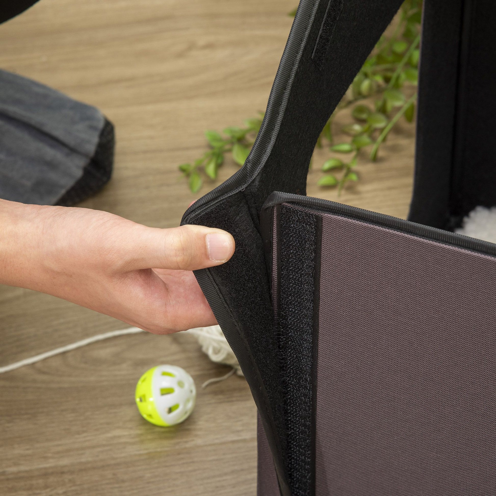 Hand adjusting the opening of a heated cat house for outdoor use designed for easy access and comfort