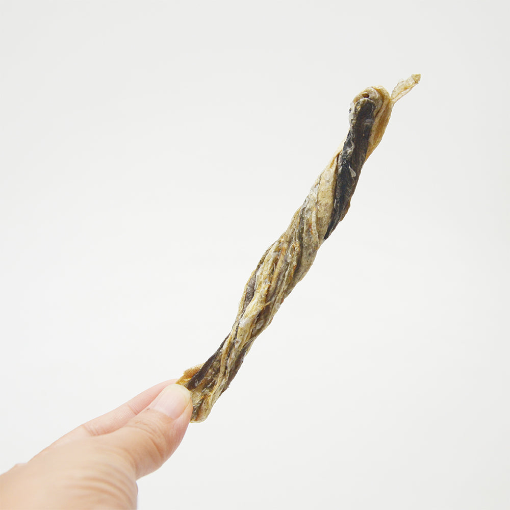 Hand holding an American Pet Supplies codfish skin dog treats stick on a white background