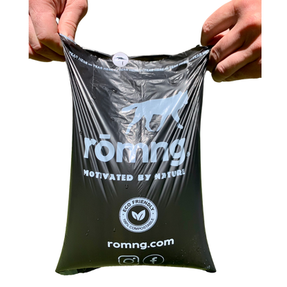 Hands holding rōmng compostable dog poop bags, showcasing their eco-friendly design and durability