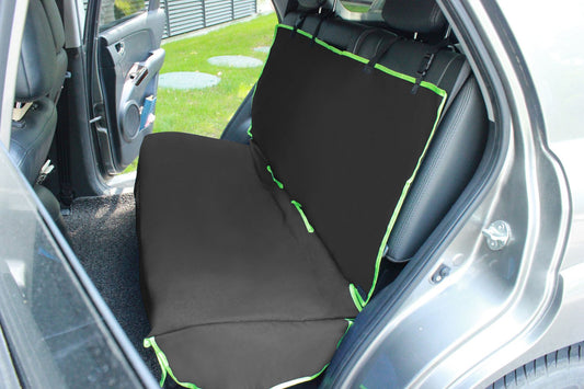 Black pet car seat protector with green trim installed on back seat of a silver car to protect upholstery