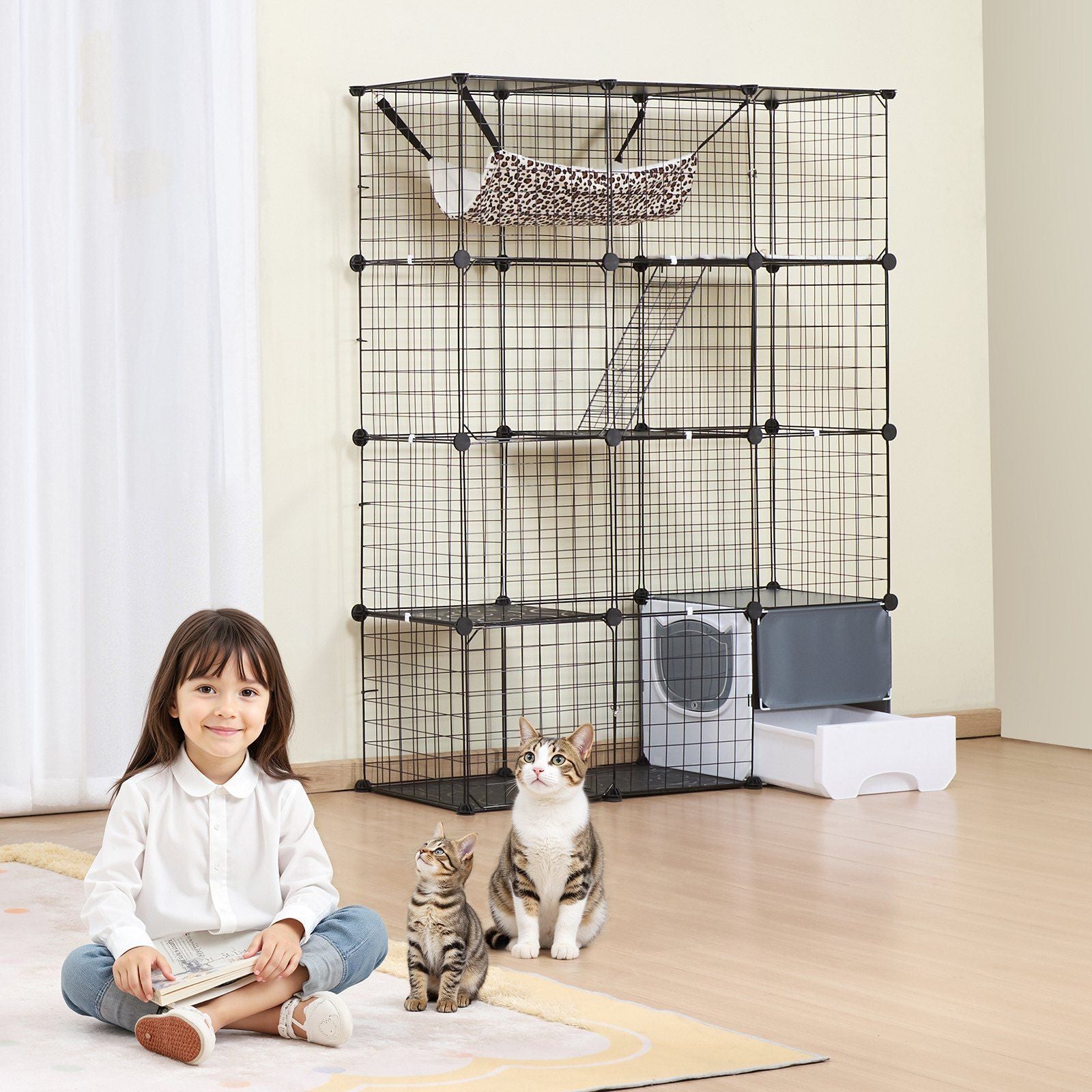 Large cat cage metal with multiple compartments and accessories next to two cats and a child sitting on the floor